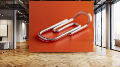 A warm orange surface with a single white paper clip Wall mural