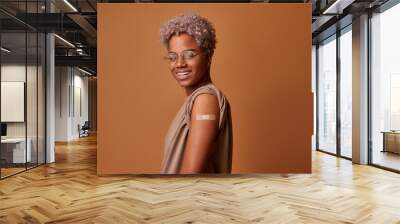 Happy African American Female Showing Vaccinated Arm After Antiviral Injection For Coronavirus Protection, Posing On Beige Studio Background. Corona Virus Vaccination, I Got My Covid-19 Vaccine. Wall mural