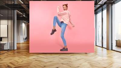 Yes I done it. Full length body shot of excited cheerful female model with joyful expression, cheers and clenches fists, celebrates her success, has appealing look, pink studio background. Achievement Wall mural