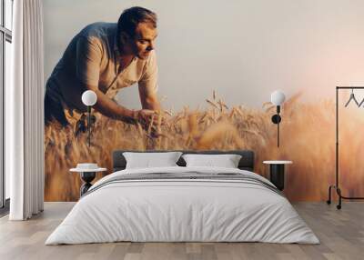 Amazing view with Man who check natural organic harvest In The Sunset Light. Farmer Walking Through Field Checking Wheat Crop.Wheat Sprouts In Farmer's Hand. Wall mural