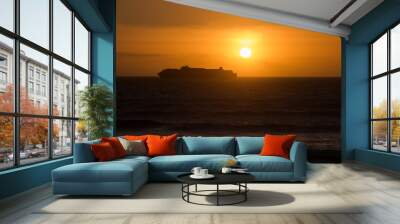 Cargo ship silhouette in orange sunset Wall mural