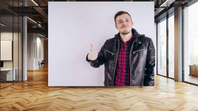 Man in trendy jacket on white background. Portrait of young male in leather jacket zipping up and smiling at camera on white background Wall mural