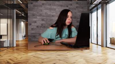 Young woman using laptop computer sitting in front of white brick wall background, people and technology, lifestyles, education, business concept Wall mural