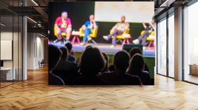 Colleagues sitting on stage during conference answering questions from audience in dark hall while presenting new project Wall mural