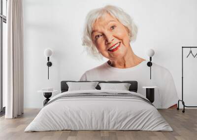 Lovely, cheerful and positive old woman on picture. Smile and look up. Dreaming about something. Wear white shirt. Elder with gray hair on picture. Isolated over white background. Wall mural