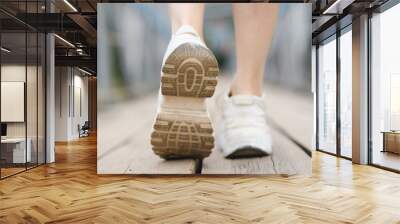 close-up view of legs in white sneakers, young beautiful caucasian woman walks on bridge in summer, leaving you, walking off, separation concept Wall mural