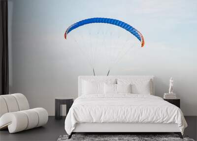 Paragliders on paraplane fly on red paraplane in sky above fields in countryside in summer at sunset Wall mural