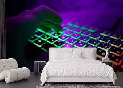 Hands on a glowing keyboard on a colored abstract background. The gamer plays the keyboard. Close-up. Wall mural