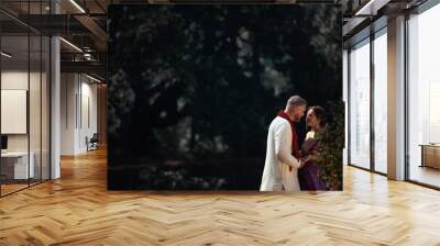 Wedding of a couple from Europe in India. A light skinned man in a traditional Indian men. white skin. Bride in beautiful sari with mehendi. Caucasian marriage. International couple.Lovely couple fit  Wall mural