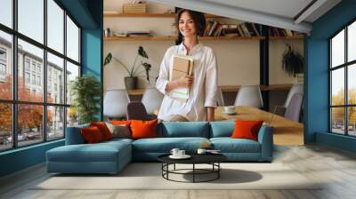 young cheerful woman in white shirt joyfully looking in camera while sitting on desk with papers and Wall mural