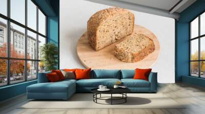 Half a loaf of homemade whole grain bread with various seeds and two slices on a white background Wall mural