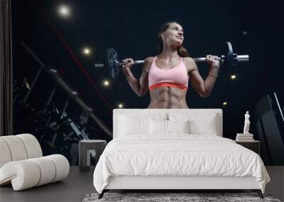 Athletic young woman posing and exercising fitness workout with weights in gym Wall mural