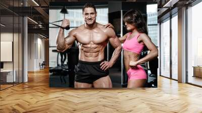 beautiful young sporty sexy couple showing muscle and workout in gym Wall mural