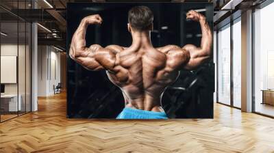 Bodybuilder strong man pumping up biceps muscles Wall mural