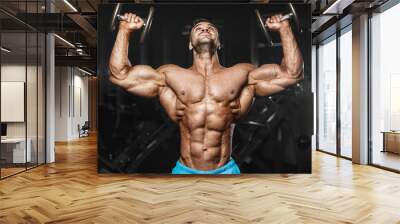 Bodybuilder strong man pumping up shoulder muscles Wall mural