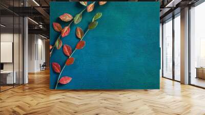 Two branches with colorful autumn leaves on dark blue-green painted wooden background  with empty space for text or image. Flat lay. Wall mural