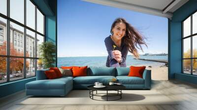 horizontal profile of a young brunette italian woman with long hair and dark blue sweater by the sea romantic with hair in the wind is happy with the deep blue sky and with a flower in her hand Wall mural