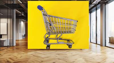 Empty shopping cart standing on yellow background Wall mural