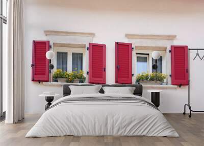 Two Italian windows on the white wall facade with open red color classic shutters and flowers on the windowsill Wall mural