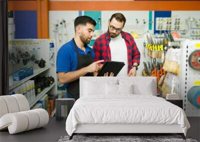 Attractive employee looking for a product with a customer at the hardware store Wall mural