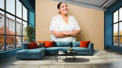 Cheerful fat latin woman smiling against a pastel yellow background Wall mural