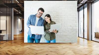 Colleagues Looking At Laptops Against Wall In Office Wall mural