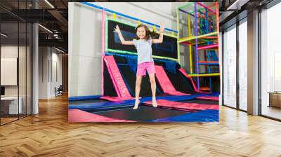 Excited kid jumping in the trampoline area in the playroom Wall mural