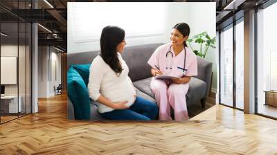 Female doctor and expectant mother laughing during a check-up Wall mural