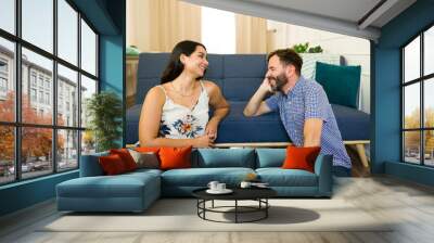 Happy young couple enjoying their time together while relaxing at home and having a cheerful conversation Wall mural