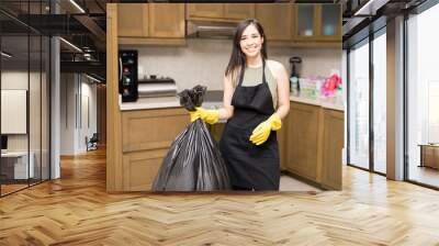 Happy young housewife holding disposal bag with trash Wall mural