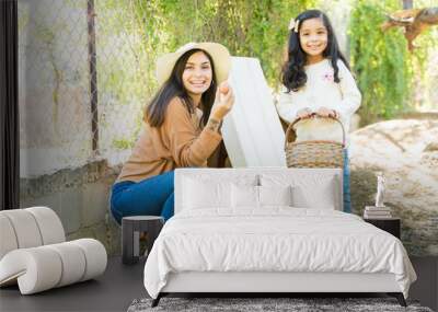 Happy Young Woman With Little Girl Showing Egg At Farm Wall mural