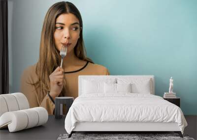 Hispanic Woman Enjoying Food Over Blue Background Wall mural