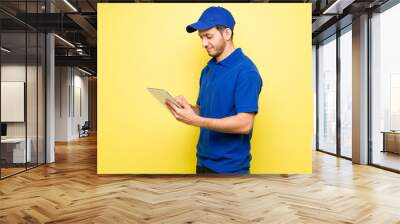 Latin delivery man with a cap using a tablet Wall mural