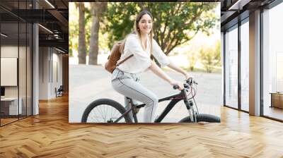 Portrait of a woman in her 30s with a professional outfit riding a bicycle Wall mural