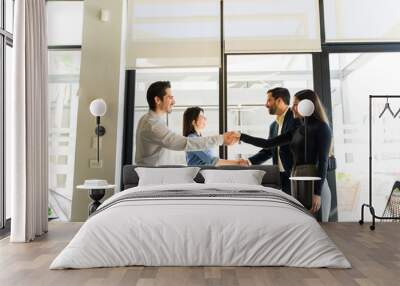 Profile view of two business partners greeting some clients and shaking hands during an office visit Wall mural