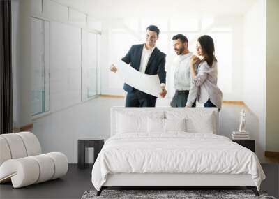 Realtor Discussing Apartment Layout With Couple In Empty Room Wall mural