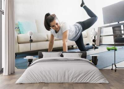 Woman doing exercises through online videos Wall mural