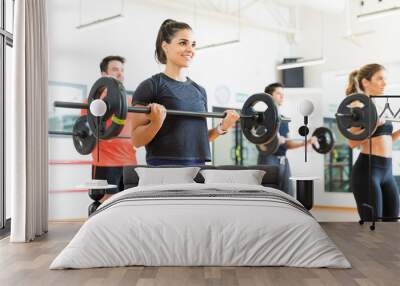 Woman Smiling While Lifting Barbell In Health Club Wall mural