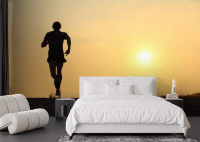 Back view of a man running on the beach at sunset Wall mural