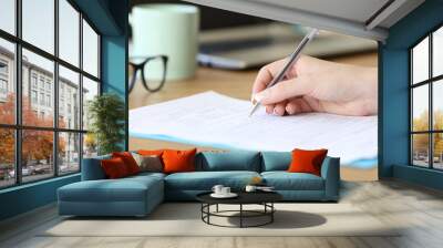 Close up of a woman hand filling form on a table Wall mural