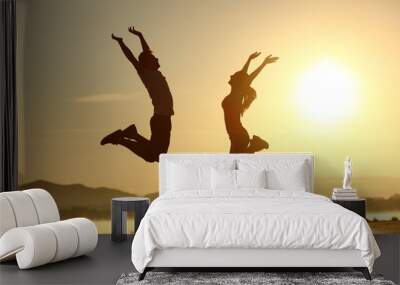 fitness couple jumping happy at sunset Wall mural