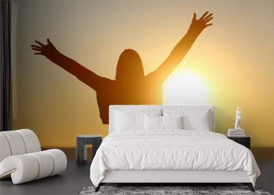 Free woman raising arms watching sun at sunrise Wall mural