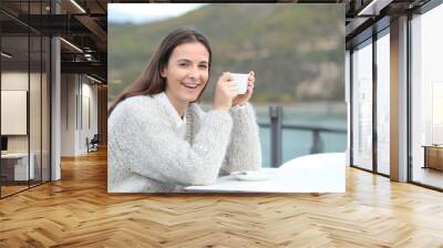 Happy girl holding coffee mug looks at camera Wall mural