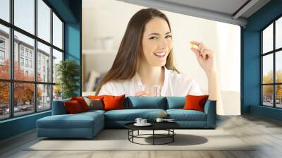 Happy lady holding and showing a vitamin pill Wall mural