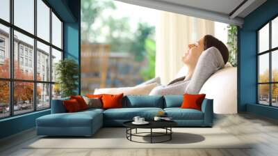 Happy woman resting on a couch at home Wall mural