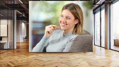 Happy woman takes a vitamin pill on a couch Wall mural