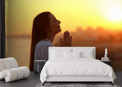 Profile of a woman praying at sunset Wall mural