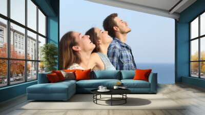 Profile of three friends breathing fresh air on the beach Wall mural