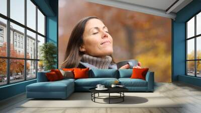 Relaxed adult woman holding coffee cup breathing in autumn Wall mural