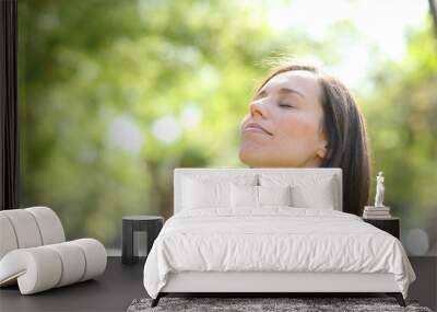 Relaxed woman breathing fresh air in a park or forest Wall mural